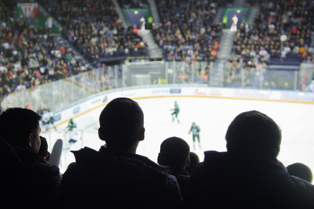 A Group Of Silhouettes Of Young People Watching Hockey Match In A Closed Stadium